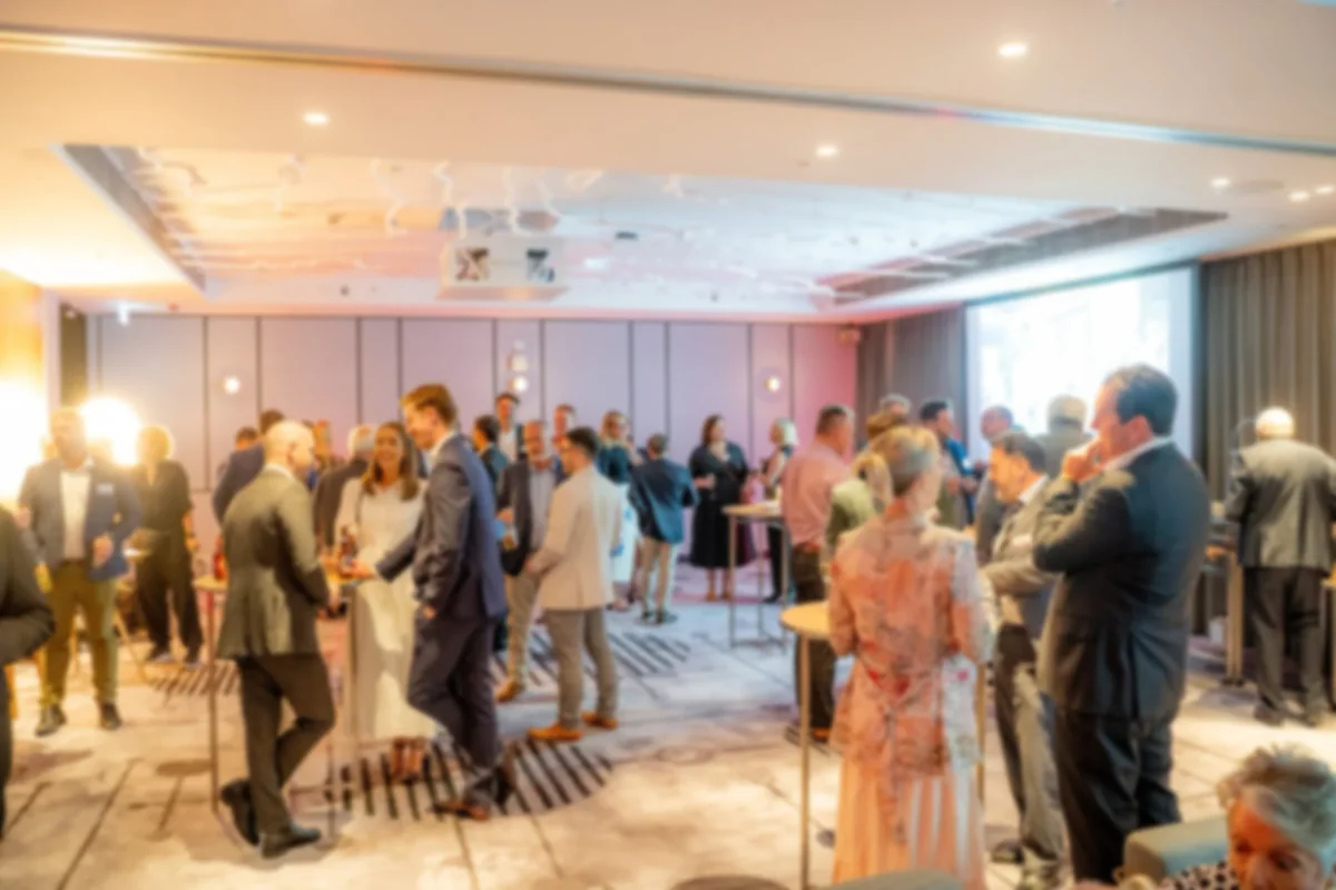 People socializing at a formal event or conference in a well-lit room with a modern design.